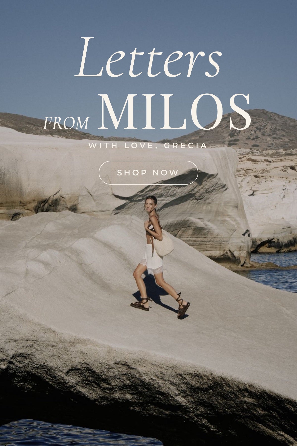  Aruzo. Modelo caminando sobre las rocas blancas de Milos con sandalias de cuero y bolso tejido.